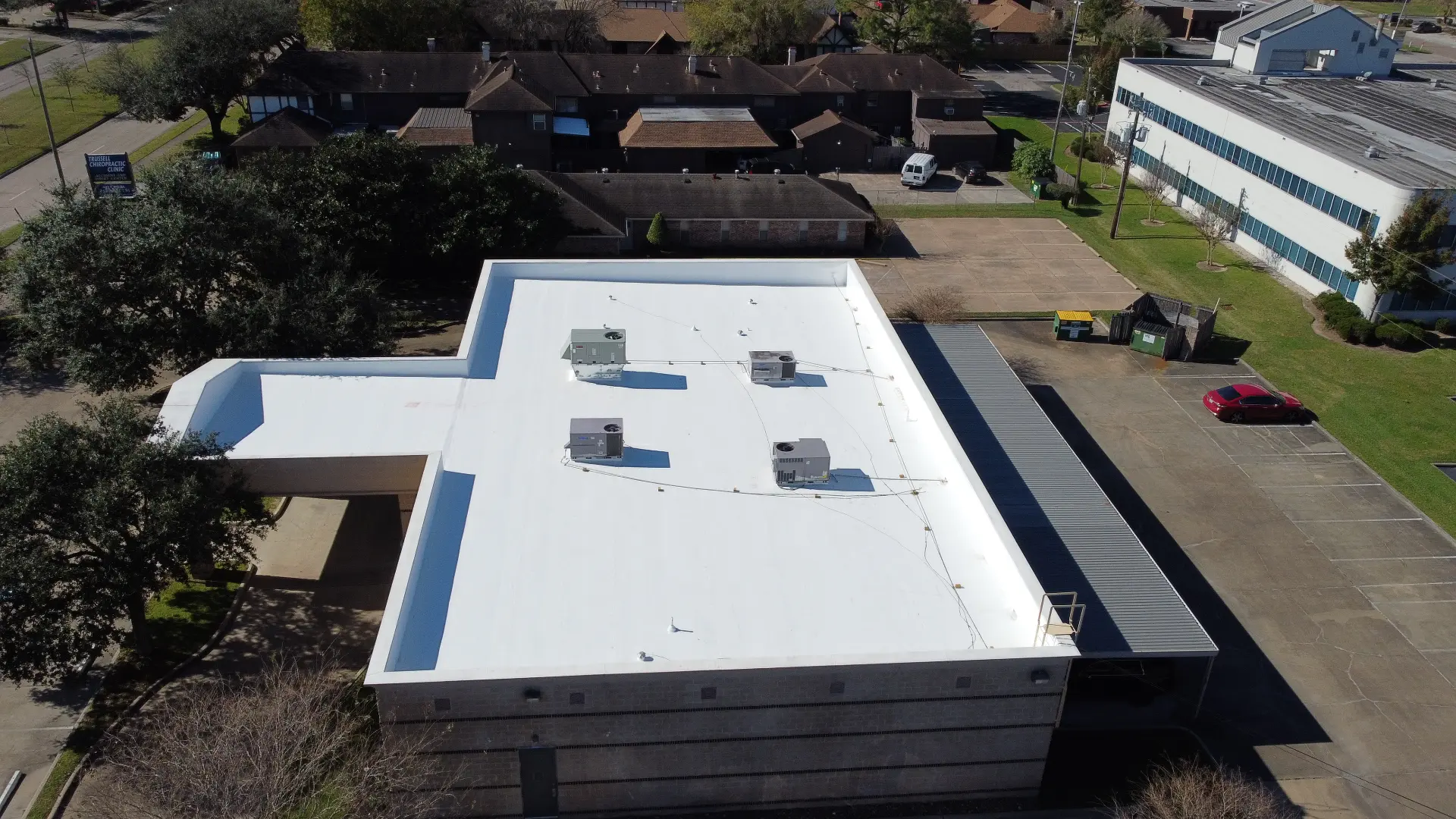 Aerial view of a completed white flat roof system with rooftop HVAC units on a Houston commercial building