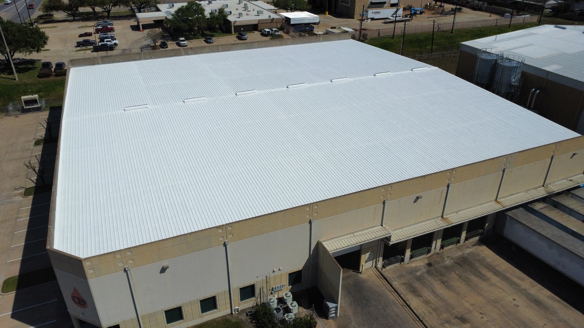 Aerial view of a Houston industrial warehouse with a freshly applied white reflective metal roof coating system